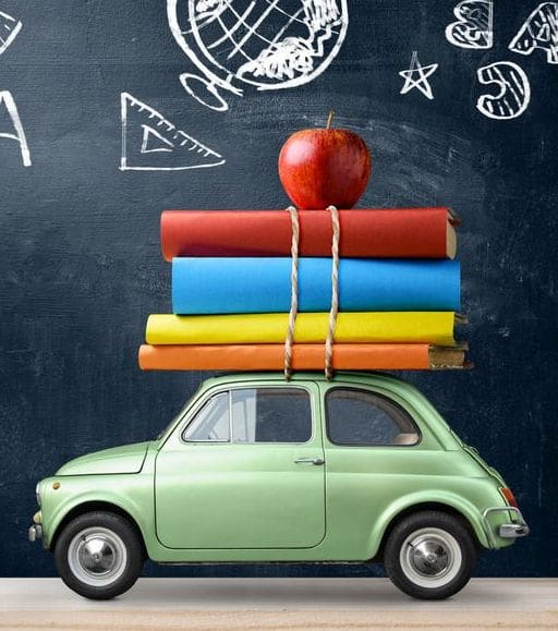 Back to school background. Car delivering books and apple against blackboard with education symbols.
